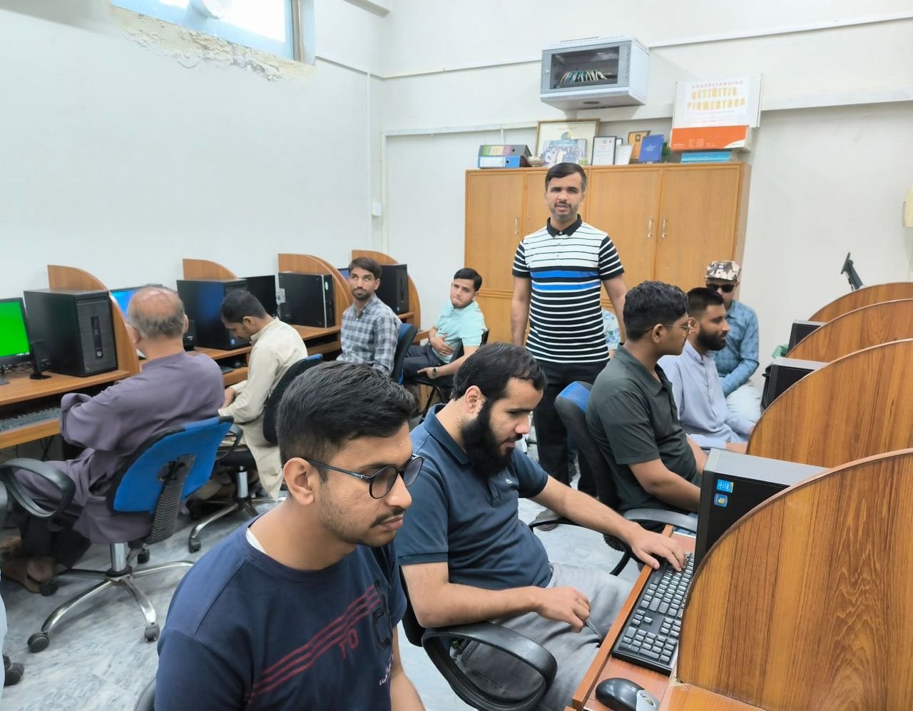 A trainer stands as participants work at computer stations during the call center accessibility training.