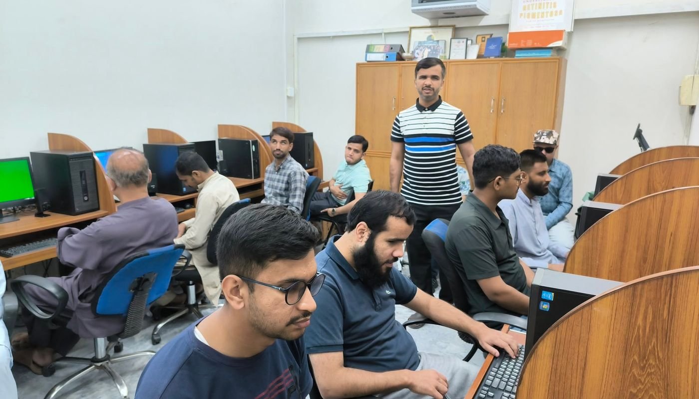 A trainer stands as participants work at computer stations during the call center accessibility training.