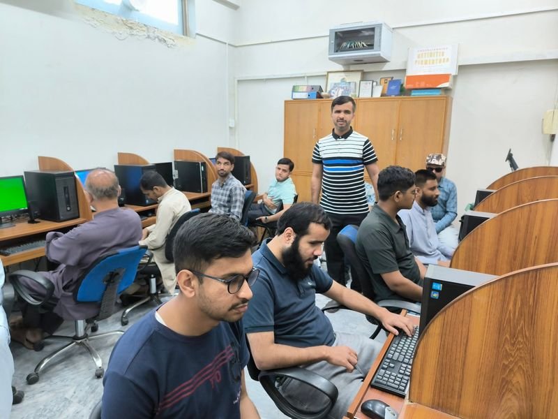 A trainer stands as participants work at computer stations during the call center accessibility training.